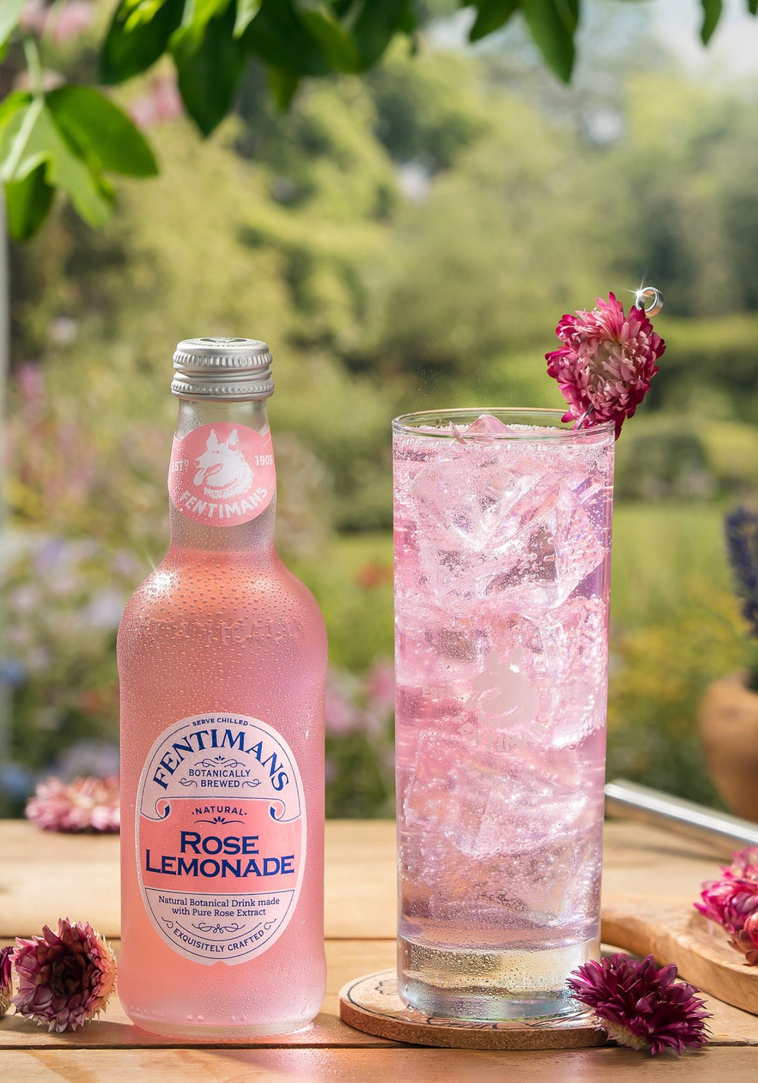 A bottle of Fentimans Rose Lemonade beside a highball cocktail garnished with lavender