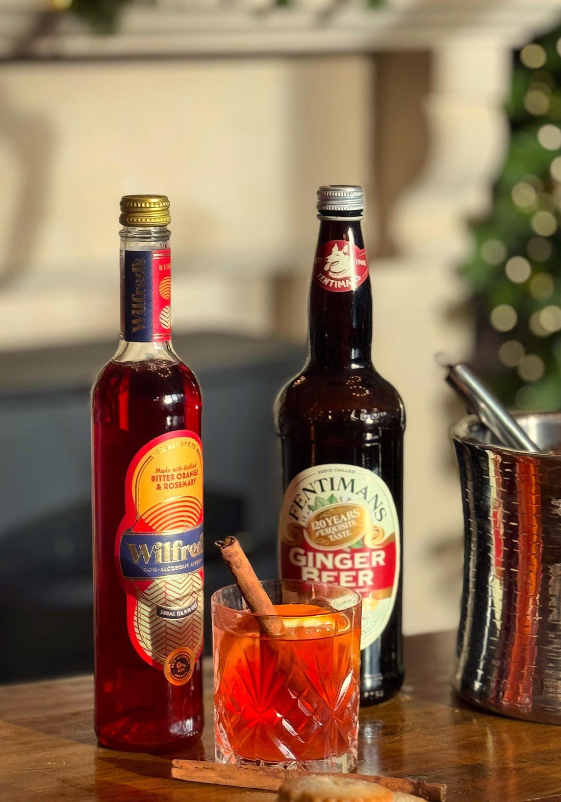 Wilfred's Ginger Mule served with a cinnamon stick beside an ice bucket and a bottle of Fentimans Ginger Beer